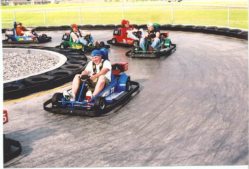 People racing on go-kart track with blue, green and red go karts