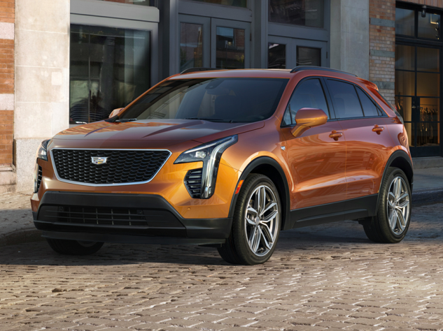 Orange Cadillac XT4 on a cobblestone street in front of a glass and brick building