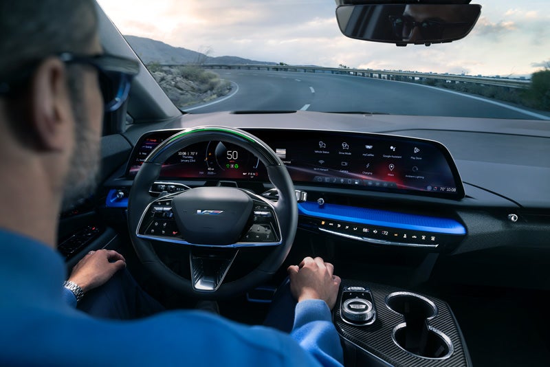 Front View of the 2026 OPTIQ-V Driving Through the Dusk Utilizing its Headlights | Rydell Cadillac in Grand Forks ND