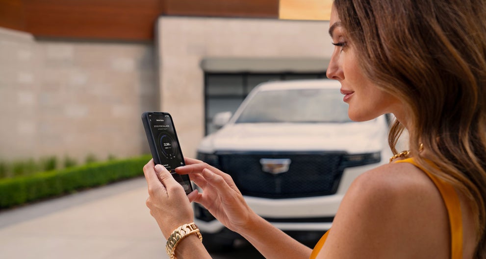 lady checking her mobile with a Cadillac vehicle background | Rydell Cadillac in Grand Forks ND