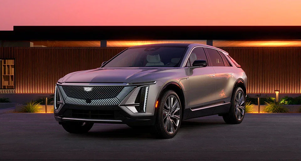 Silver 2023 Cadillac Lyriq in front of a modern house at sunset